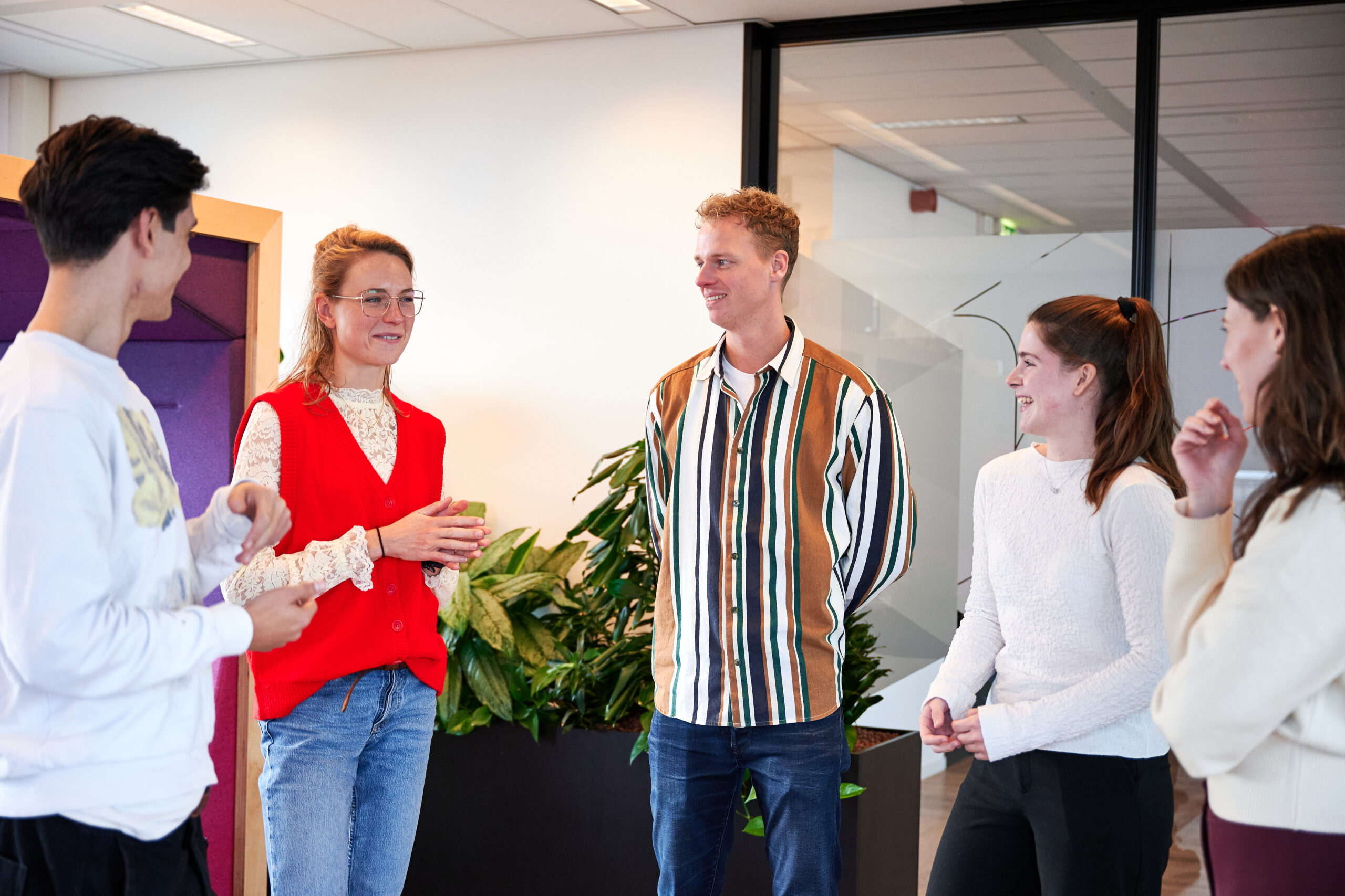 Collega's op kantoor – grote groep mensen zijn druk in gesprek met elkaar – tevreden gezichten